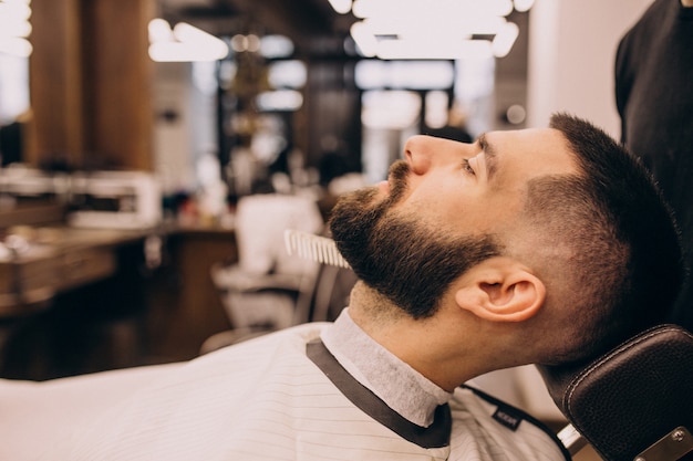 Uomo in un salone di barbiere facendo taglio di capelli e taglio della barba