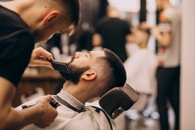 Мужчина в парикмахерской делает прическу и бороду