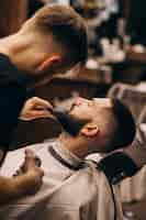 Free photo man at a barbershop salon doing haircut and beard trim