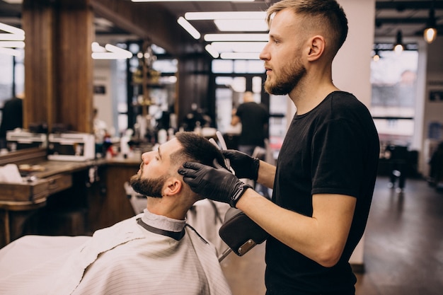 Uomo in un salone di barbiere facendo taglio di capelli e taglio della barba