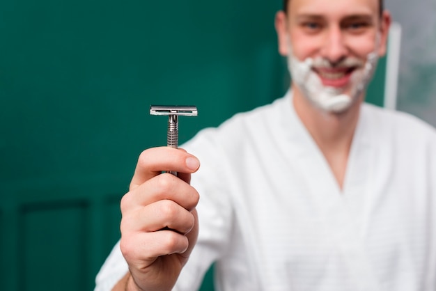 Man in bathrobe holding razor