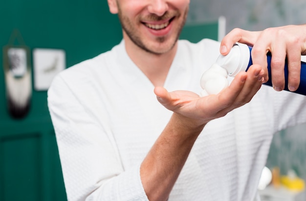 Man in bathrobe spraying shaving foam in hand