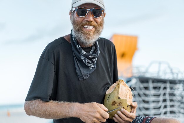 man on the beach opens a coconut