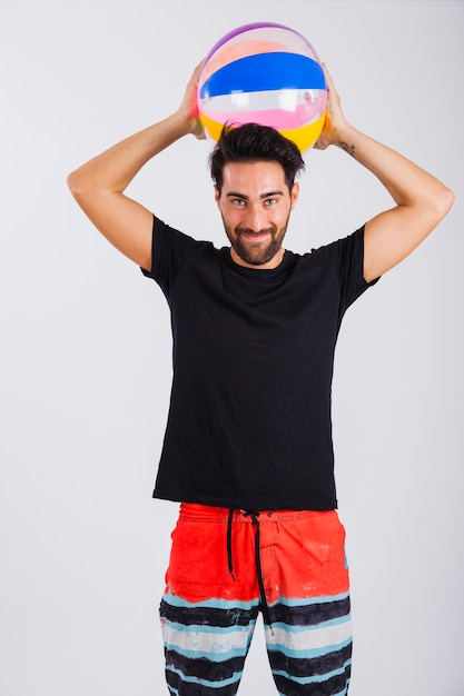 Free photo man in beachwear holding ball behind head