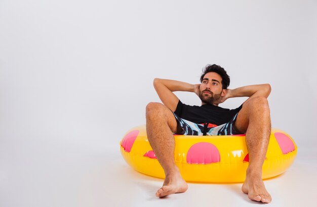 Man in beachwear lying in floating tube