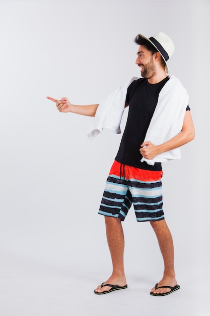 Man in beachwear with towel pointing somewhere