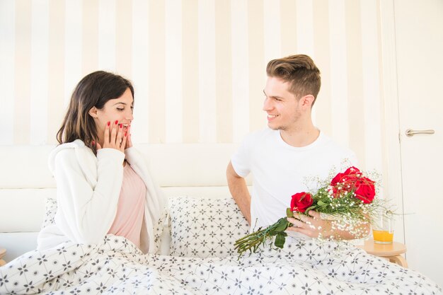 Man on bed making surprise for woman