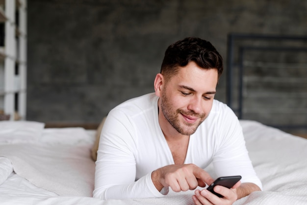 Foto gratuita uomo a letto digitando sul telefono