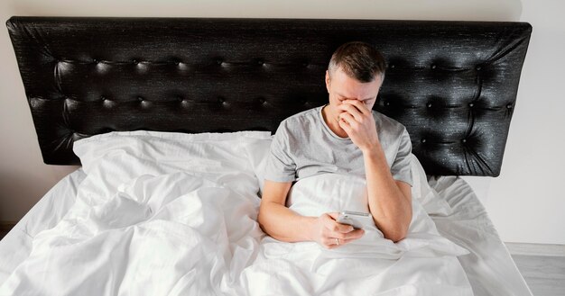 Uomo a letto utilizzando il cellulare