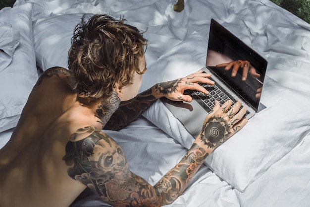 a man in bed working on a laptop, checking mail, watching a movie, listening to music