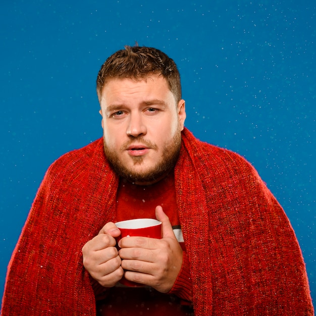 Free photo man being cold while holding a cup of tea