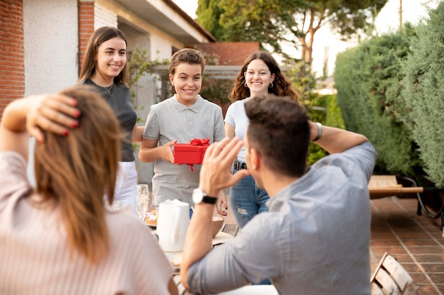 Free photo man being surprised with gift at family gathering