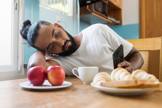 Foto gratuita l'uomo è stanco mentre fa colazione