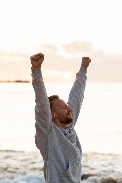 Free photo man being victorious next to the sea