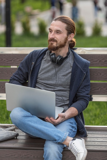 Man on bench outdoors with laptop
