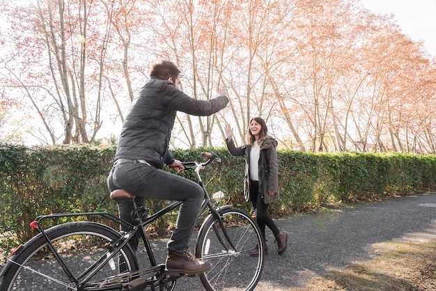 Man on bicycle greeting woman in park 