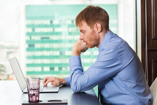 Man biting his nails while looking at a laptop