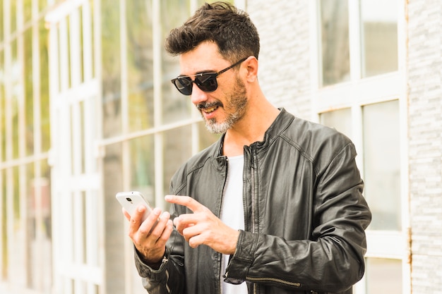 Man in black jacket wearing sunglasses using mobile phone