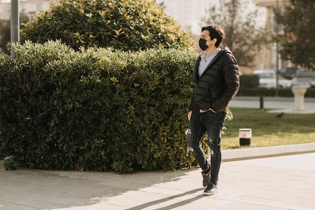 Man in black leather jacket and black face mask walking in the park. High quality photo