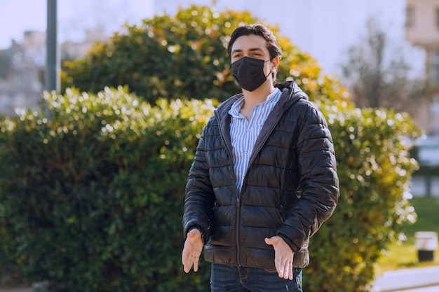 검은 가죽 재킷과 공원에서 산책하는 검은 얼굴 마스크에 남자. 고품질 사진