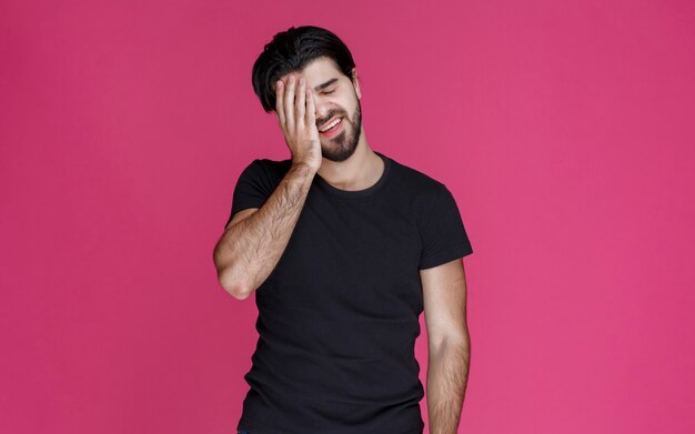 Man in black shirt covers his head and feels headache