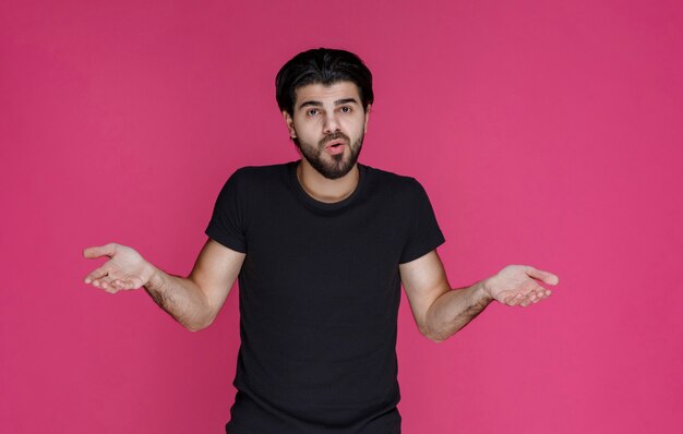 Man in black shirt looks thoughtful, confused and hesitating