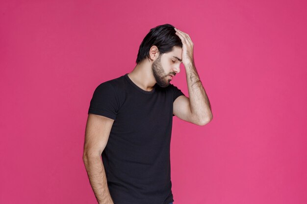 Man in black shirt looks tired, bored and sleepy