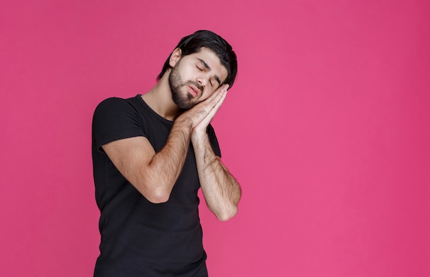 Man in black shirt looks tired, bored and sleepy