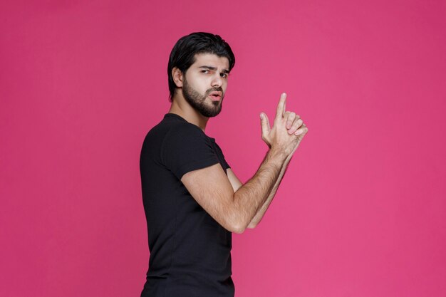 Man in black shirt making hand gun sign