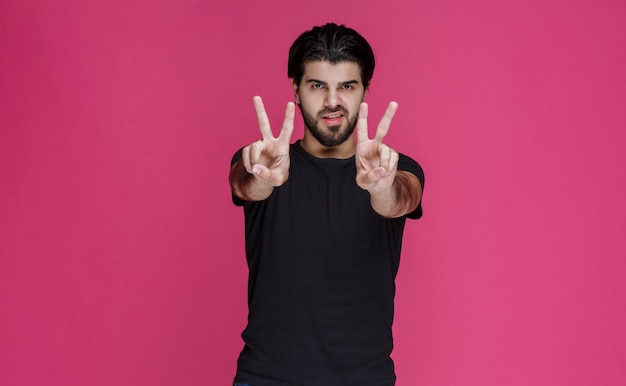 Free photo man in black shirt making peace hand sign