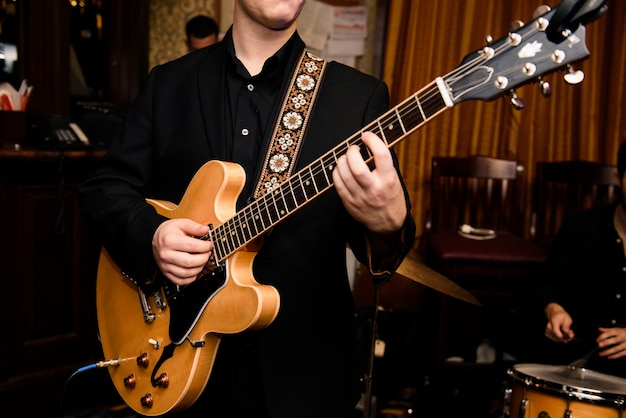 Man in black shirt plays on guitar