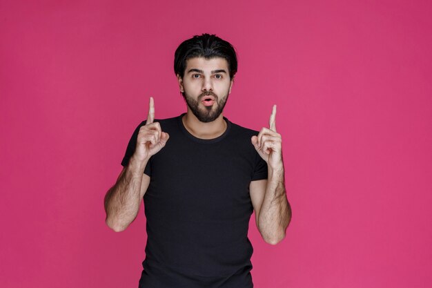 Man in black shirt pointing at something or introducing someone