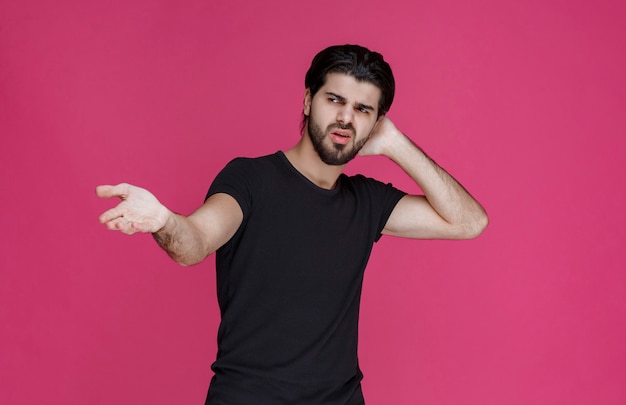 Man in black shirt pointing at something or introducing someone