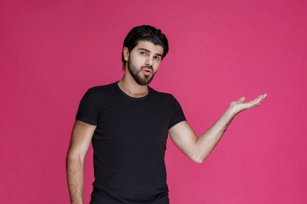 Man in black shirt pointing at something or introducing someone