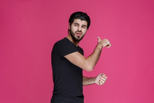 Man in black shirt pointing at something or introducing someone