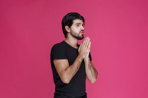 Man in black shirt praying and dreaming about something