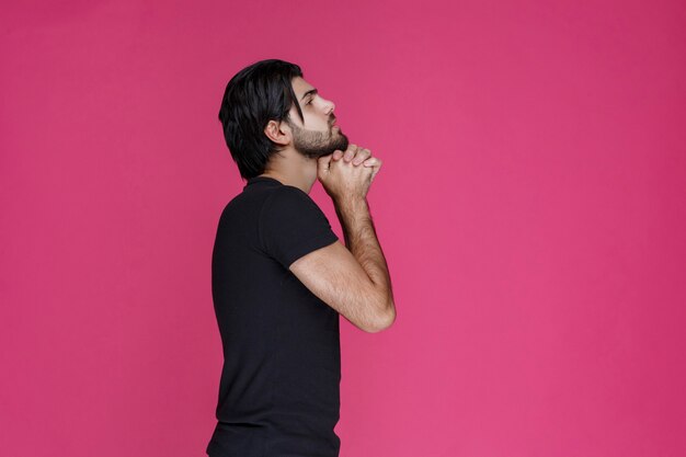 Man in black shirt praying and dreaming about something