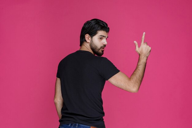 Man in black shirt showing direction, view from behind