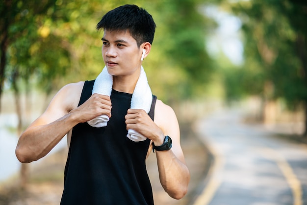 A man in a black shirt stood and held a handkerchief over his neck to wipe his face.