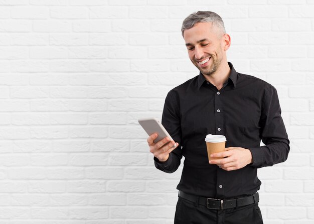 Man in black suit holding phone and coffee