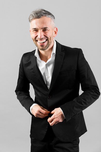 Man in black suit smiles and button up his jacket