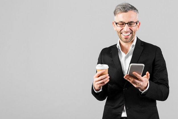 Man in black suit smiles at his mobile phone