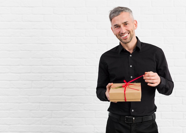Free photo man in black suit unwrapping a gift