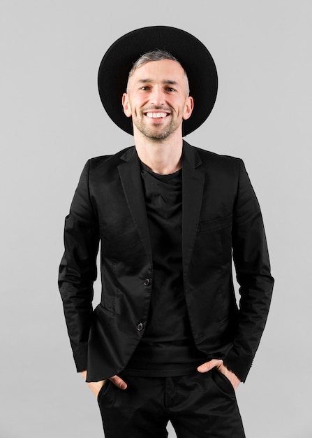 Free photo man in black suit with hat and hands in pockets