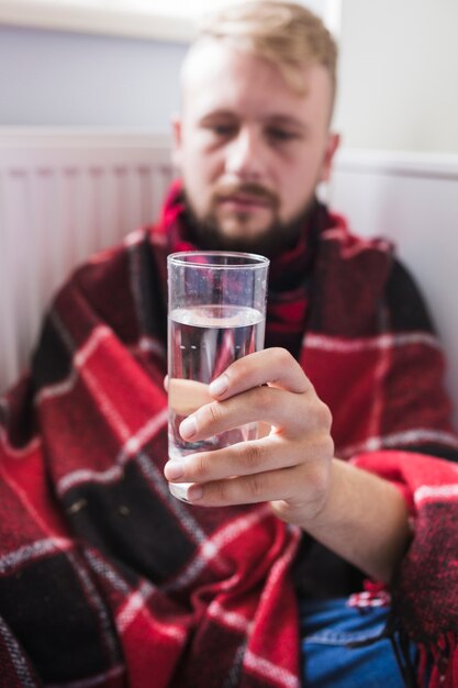 水のガラスで毛布の下の男