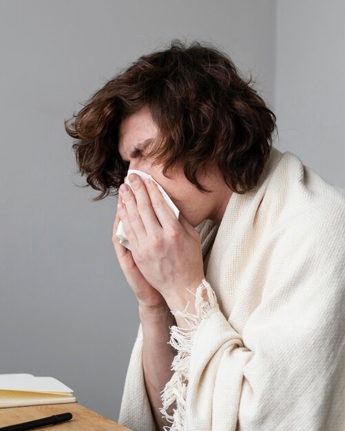 man blowing his nose indoors
