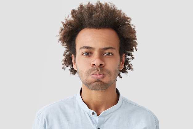 Free photo man blows cheeks, has discontent expression, being dissatisfied with something