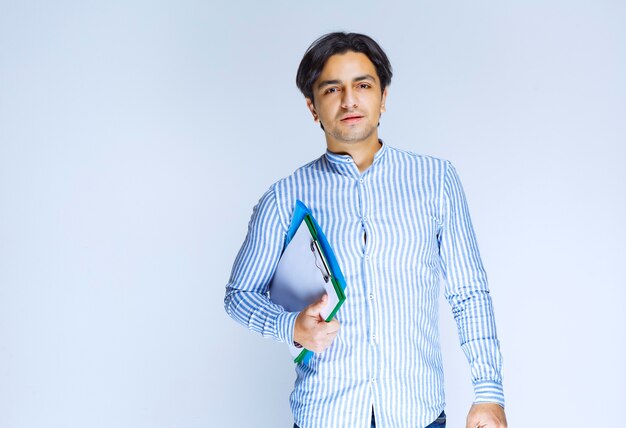 Man in blue shirt holding green reporting folder. High quality photo