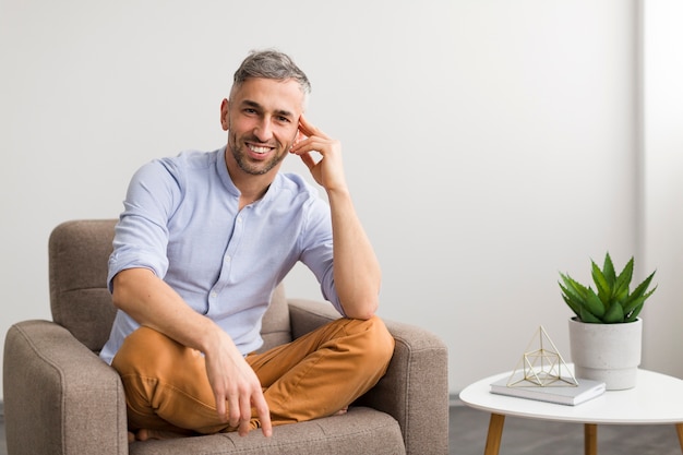 Man in blue shirt sitting on chair and smiles