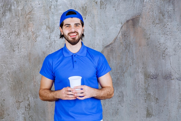 持ち帰り用の飲み物を持っている青い制服を着た男。